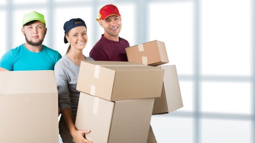 Local movers carrying furniture through a Shadwell residential building entrance